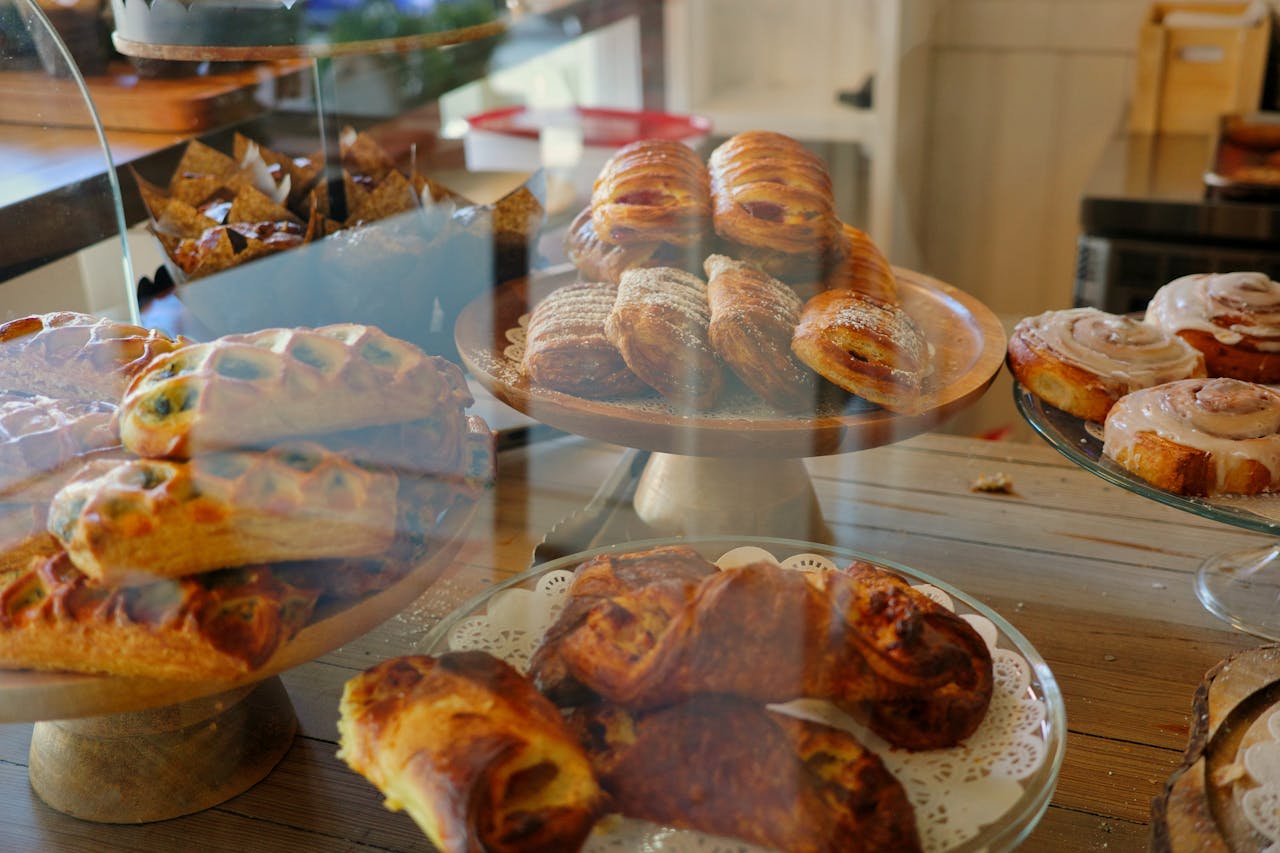 A variety of pastries and baked goods displayed behind a glass counter in a bakery.